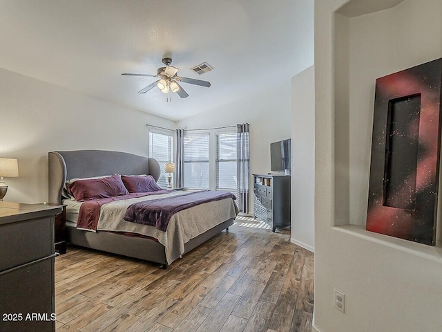bedroom featuring lofted ceiling, a ceiling fan, baseboards, visible vents, and wood finished floors