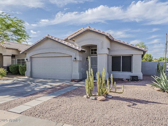 ranch-style house featuring an attached garage, stucco siding, a tile roof, fence, and concrete driveway