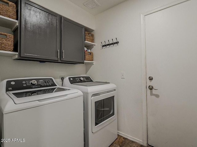 laundry room featuring washing machine and dryer, baseboards, dark wood-style flooring, visible vents, and cabinet space