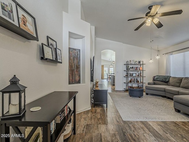 living room featuring arched walkways, dark wood-style floors, and a ceiling fan