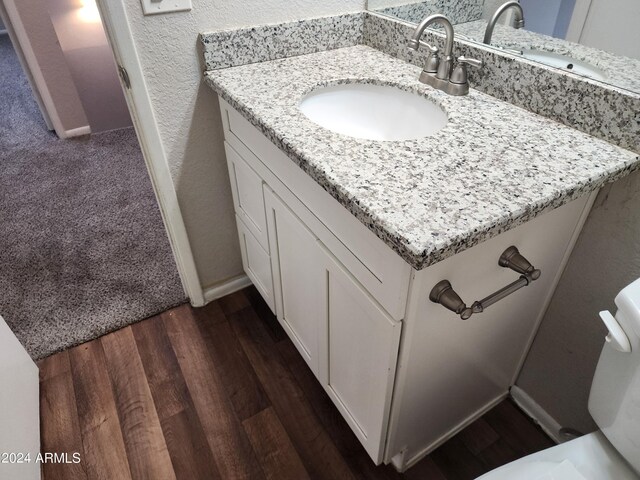 bathroom featuring wood-type flooring, vanity, and toilet