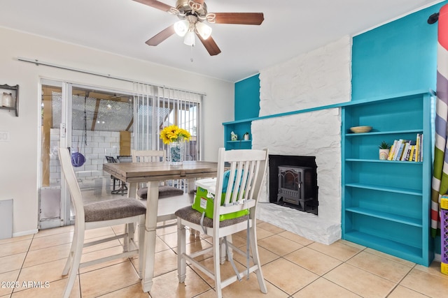 tiled dining space featuring ceiling fan and a wood stove