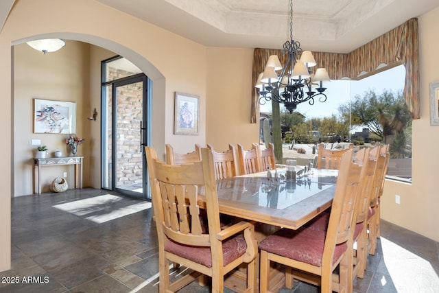 dining area featuring an inviting chandelier and a raised ceiling