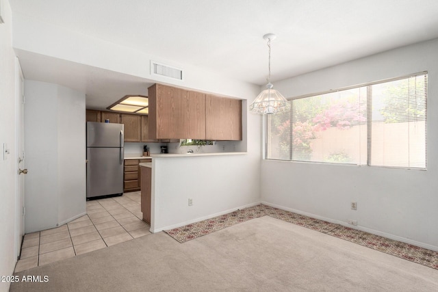 10235 N 31st St Unit 2, Phoenix, AZ 85028 - kitchen with freestanding refrigerator, light colored carpet, light countertops, a peninsula, and a chandelier