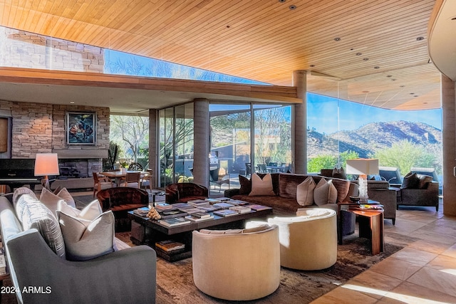 interior space featuring an outdoor stone fireplace, wooden ceiling, vaulted ceiling, a mountain view, and light tile patterned floors