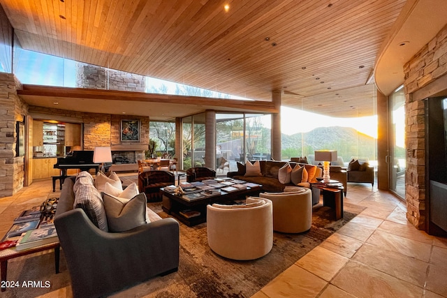 living room featuring a mountain view, a stone fireplace, wooden ceiling, and lofted ceiling