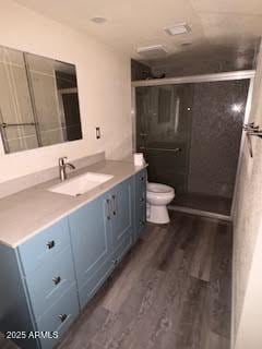 bathroom featuring wood-type flooring, toilet, vanity, and walk in shower