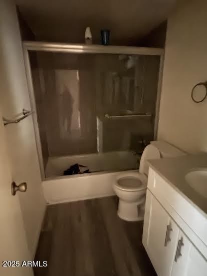 full bathroom with wood-type flooring, toilet, combined bath / shower with glass door, and vanity