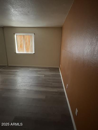 unfurnished room with a textured ceiling and dark hardwood / wood-style flooring