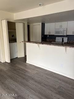 kitchen with stove, dark hardwood / wood-style floors, white cabinets, and a kitchen bar