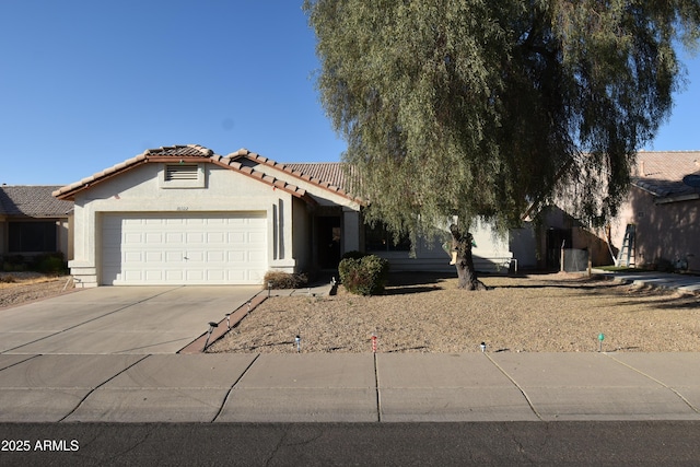 view of front of property with concrete driveway, a tiled roof, an attached garage, and stucco siding