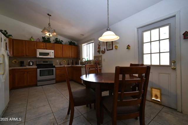 dining space with vaulted ceiling and light tile patterned floors