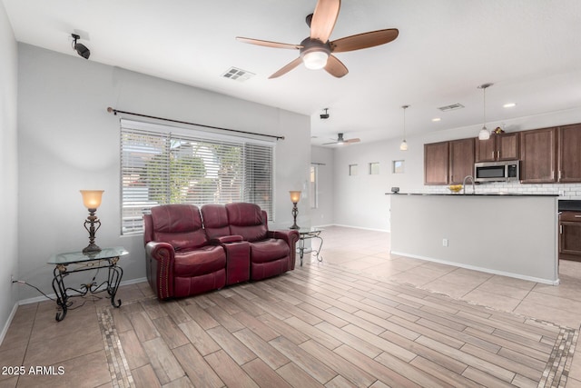 living room featuring ceiling fan, light hardwood / wood-style flooring, and sink