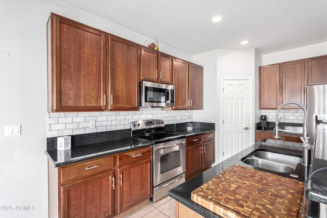 kitchen with light tile patterned floors, backsplash, appliances with stainless steel finishes, and sink