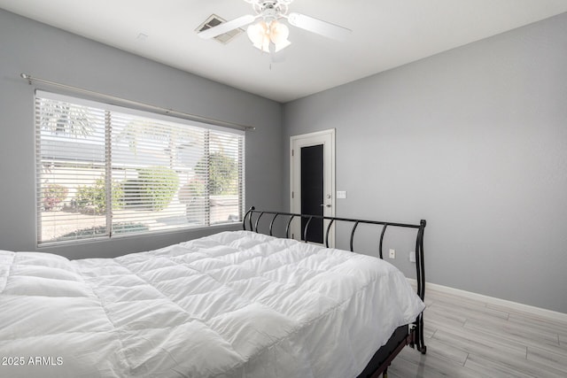 bedroom with light wood-type flooring, ceiling fan, and multiple windows