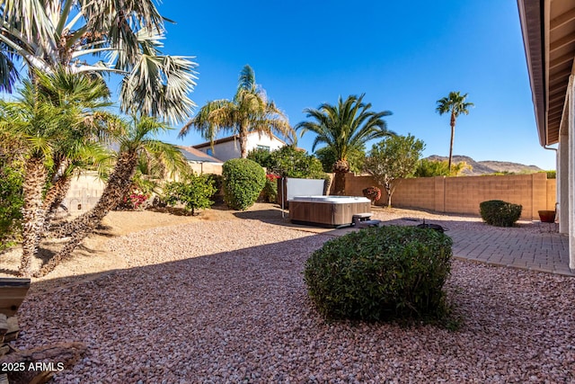 view of yard featuring a hot tub, a patio area, and a mountain view