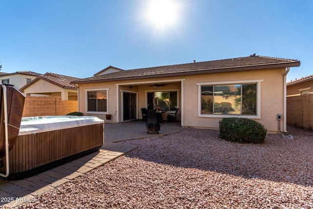 rear view of house with a hot tub and a patio