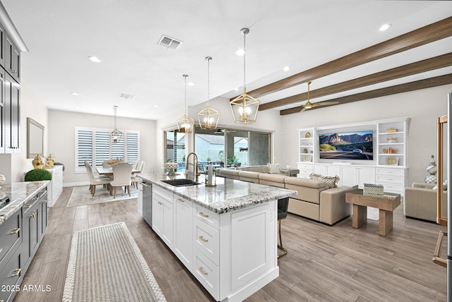 kitchen with visible vents, a sink, stainless steel dishwasher, and light stone countertops