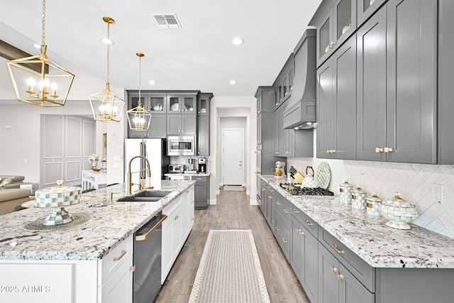 kitchen featuring appliances with stainless steel finishes, gray cabinets, a sink, and visible vents