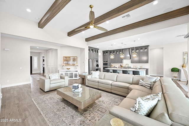 living area featuring baseboards, visible vents, ceiling fan, beamed ceiling, and wood finished floors