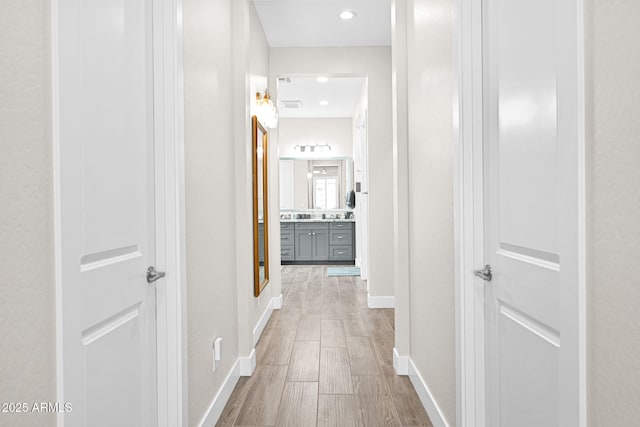 hallway featuring recessed lighting, baseboards, and wood finished floors