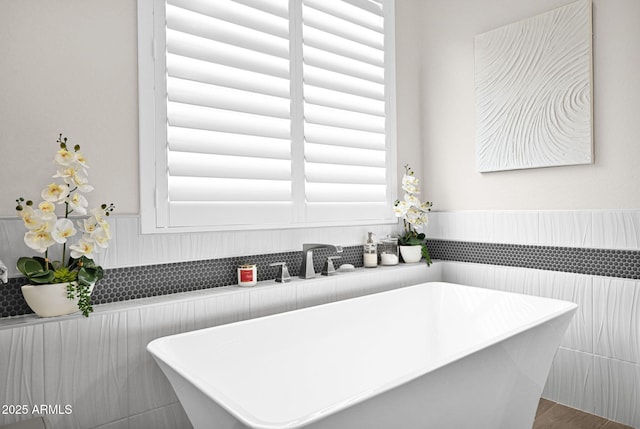 bathroom with a soaking tub, a sink, and wainscoting