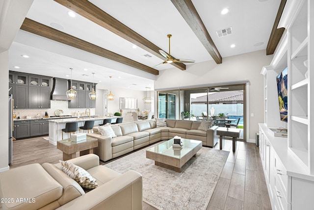 living room featuring beam ceiling, light wood finished floors, recessed lighting, visible vents, and a ceiling fan