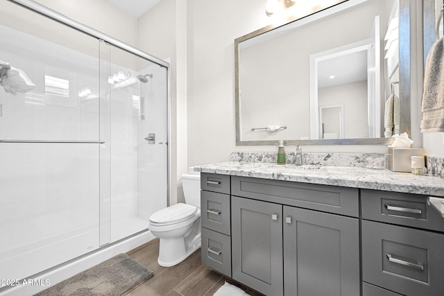 full bath featuring vanity, a shower stall, toilet, and wood finished floors