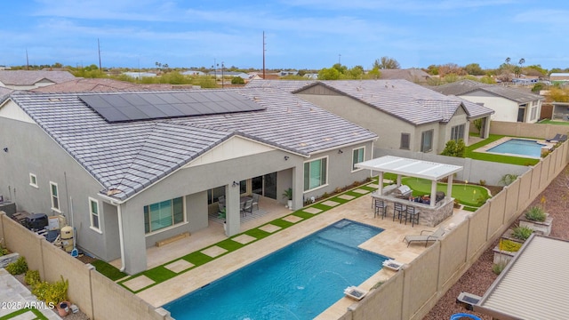 back of property featuring a fenced backyard, a patio, outdoor dry bar, and solar panels