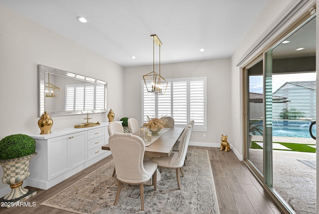 dining area with a notable chandelier, plenty of natural light, baseboards, and wood finished floors