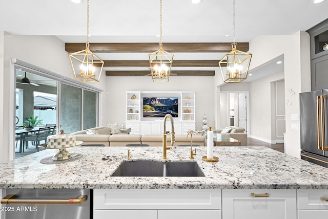 kitchen with light stone counters, open floor plan, a sink, and high end fridge