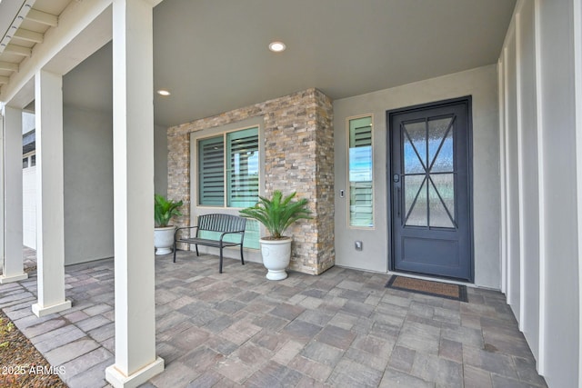 property entrance with a porch and stone siding