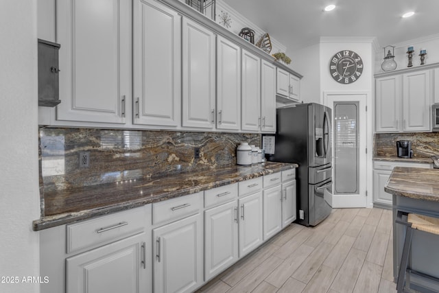 kitchen featuring dark stone countertops, white cabinets, backsplash, stainless steel appliances, and crown molding