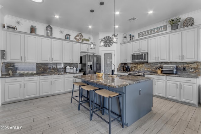 kitchen with stainless steel appliances, a center island with sink, and white cabinets