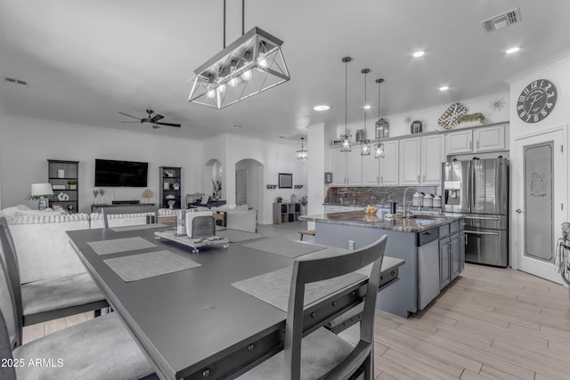 kitchen with decorative light fixtures, an island with sink, sink, gray cabinetry, and stainless steel appliances