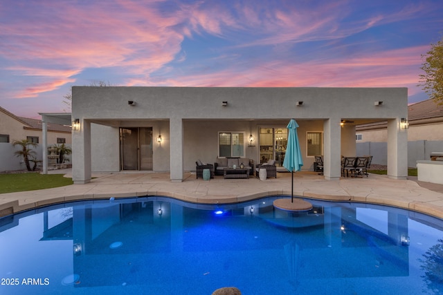 pool at dusk with a patio area and outdoor lounge area