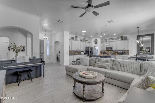 living room featuring ceiling fan with notable chandelier and light hardwood / wood-style floors