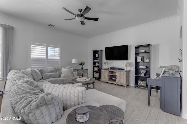 living room featuring ornamental molding, ceiling fan, and light wood-type flooring