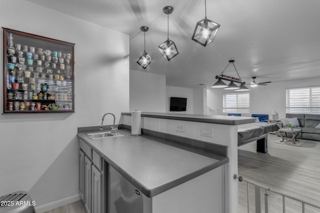 kitchen featuring sink, kitchen peninsula, pendant lighting, ceiling fan, and light hardwood / wood-style floors