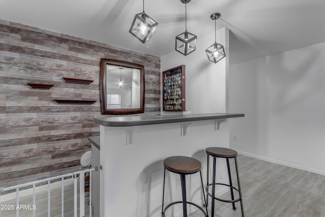 bar featuring hanging light fixtures and light hardwood / wood-style flooring