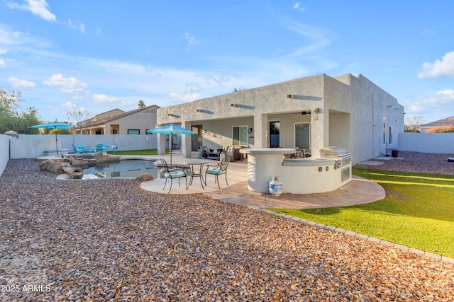 rear view of house featuring exterior kitchen, a patio, an outdoor bar, and a fenced in pool