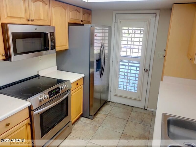 kitchen with light tile patterned flooring, appliances with stainless steel finishes, and light brown cabinetry