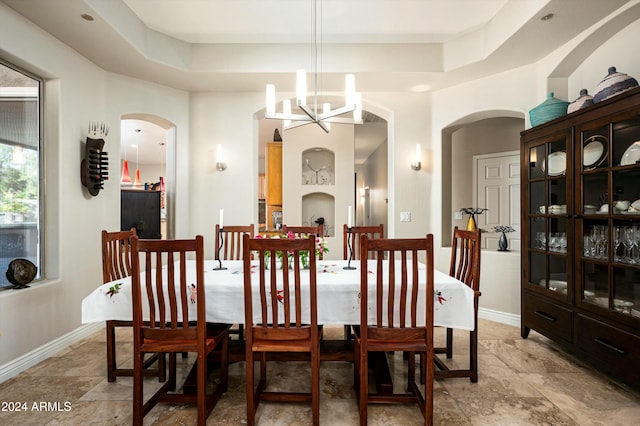 dining area featuring a tray ceiling and a notable chandelier