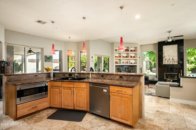 kitchen with pendant lighting, dark stone countertops, sink, and appliances with stainless steel finishes