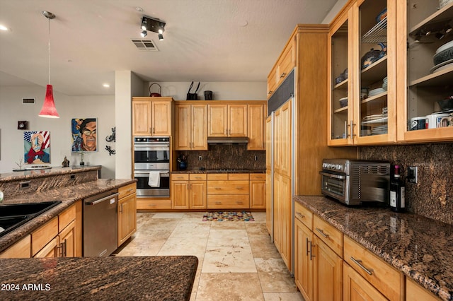 kitchen with pendant lighting, backsplash, dark stone counters, sink, and stainless steel appliances