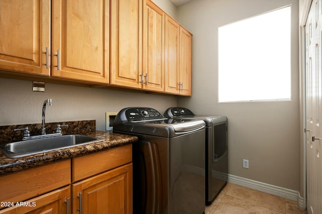 clothes washing area featuring separate washer and dryer, sink, light tile patterned floors, and cabinets