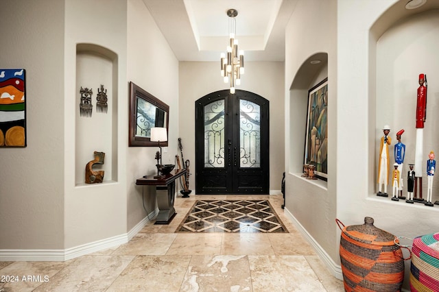 foyer with french doors and a raised ceiling