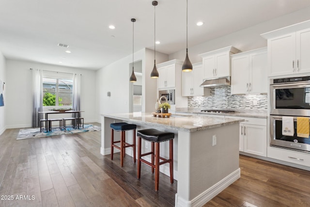 11872 W Duane Ln, Peoria, AZ 85383 - kitchen with stainless steel appliances, decorative backsplash, under cabinet range hood, dark wood finished floors, and a kitchen island with sink