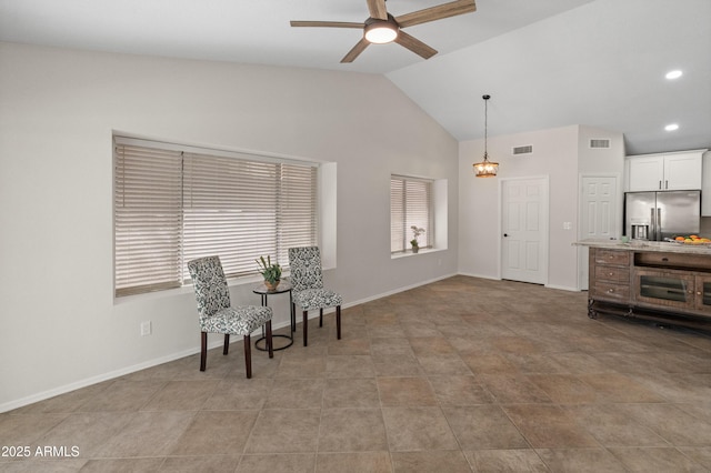 living area featuring visible vents, baseboards, vaulted ceiling, and ceiling fan with notable chandelier