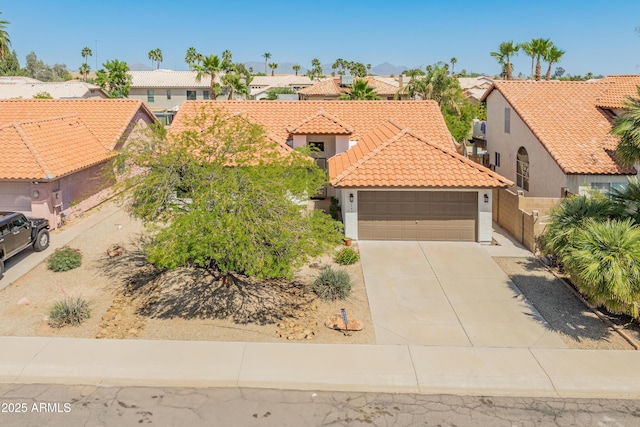 mediterranean / spanish-style home with a residential view, an attached garage, a tile roof, stucco siding, and concrete driveway